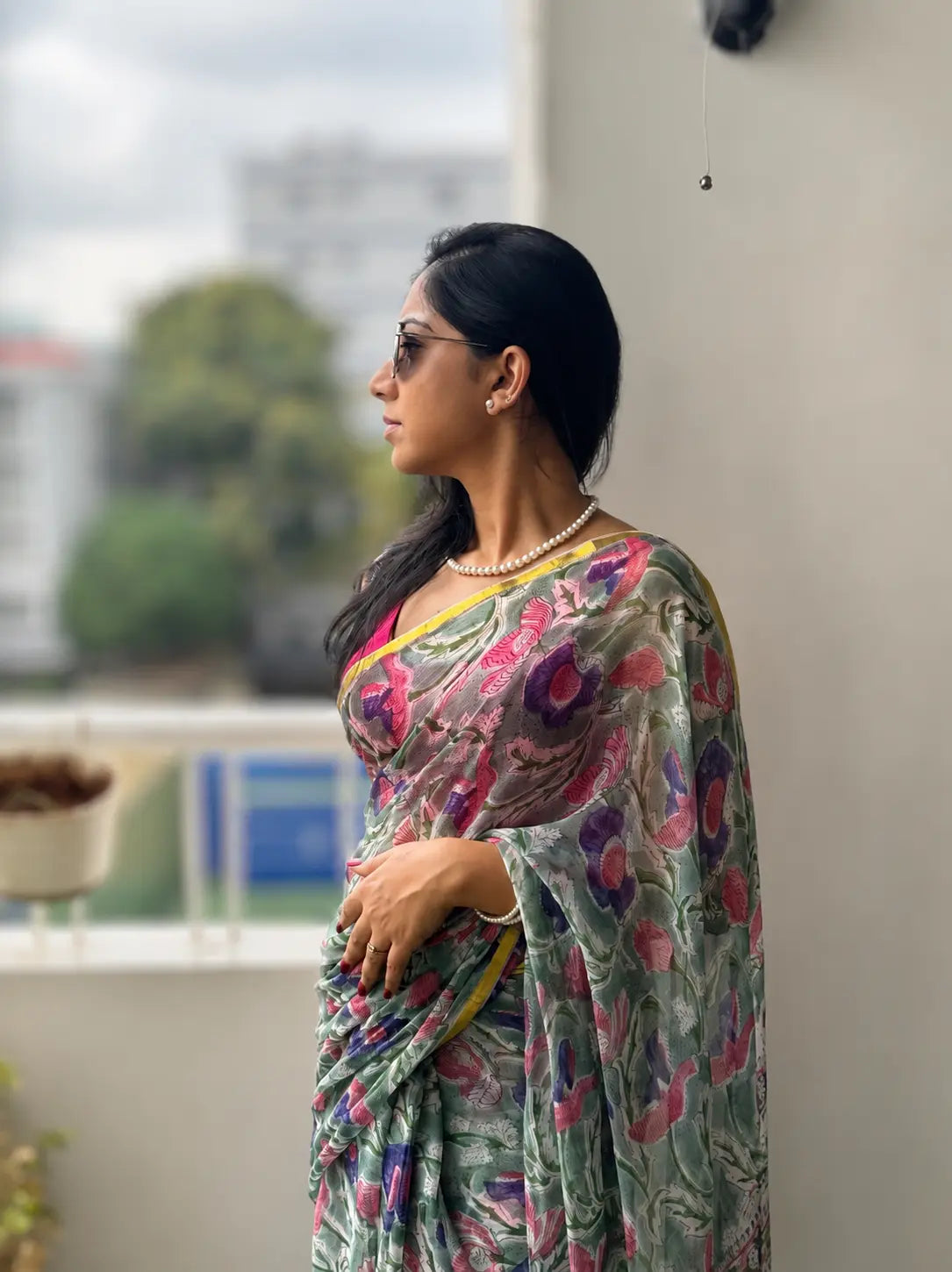 Woman wearing Tiulip Garden Whisper white floral chiffon saree with red and green floral prints and elegant flowing drape.