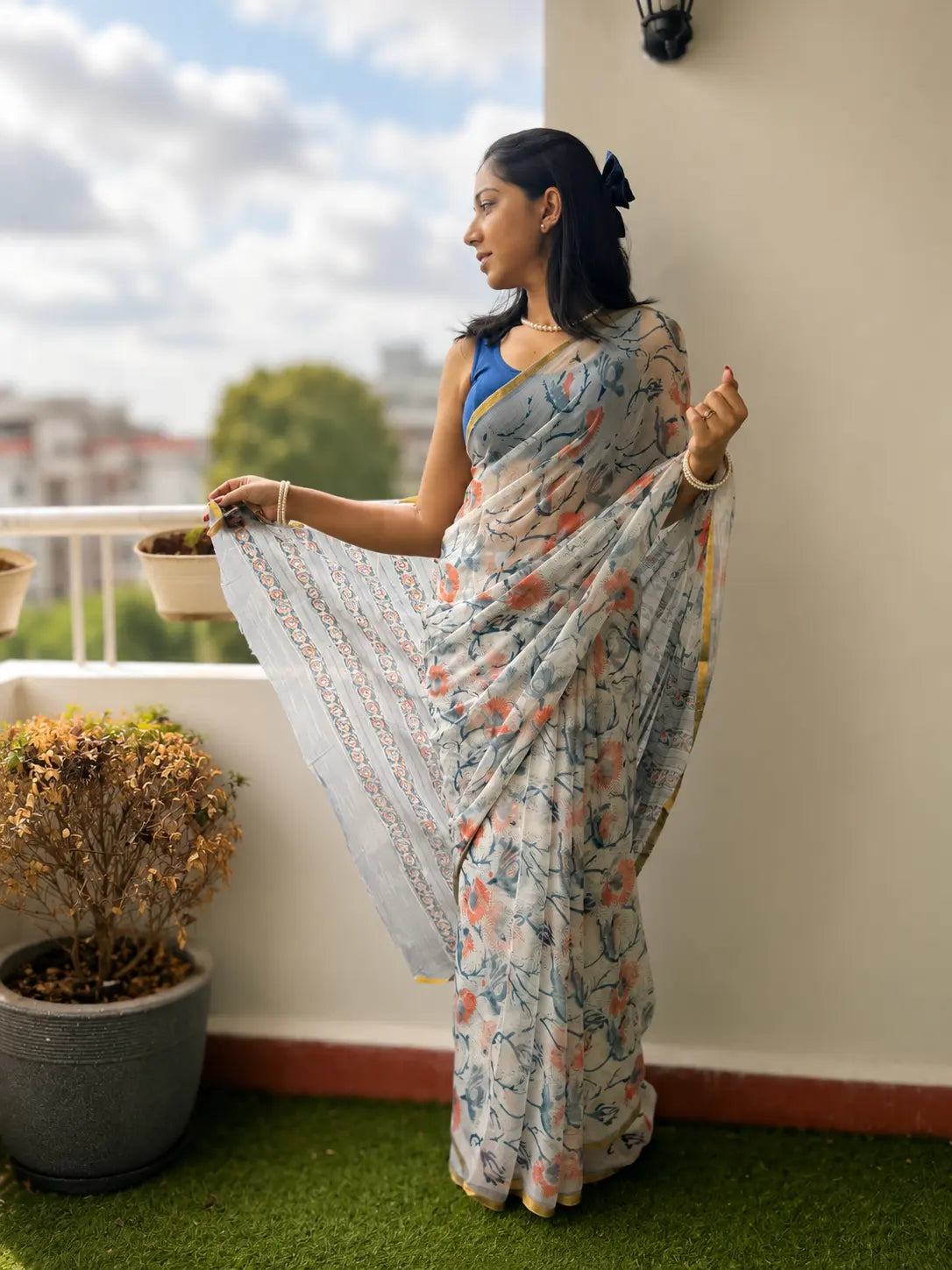 Woman wearing Tiulip Azure Bloom white floral chiffon saree with blue floral prints and graceful flowing drape